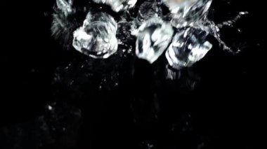 Siyah arka planda buz küplerinin düşüşü. Yavaş çekim.