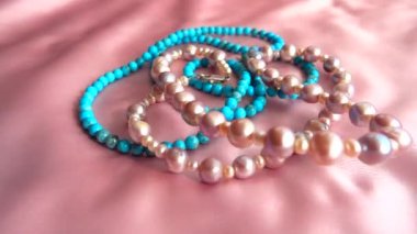 İnci bir kolye ve yüzükler ipeğin üzerine düşer. Yavaş çekim.