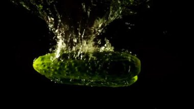 Suya düşen salatalıklar. Ağır çekim. Siyah arkaplan.