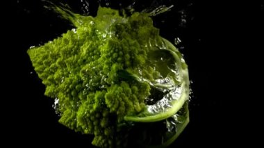 Suya düşen brokoli lahanası. Ağır çekim. Siyah arkaplan.