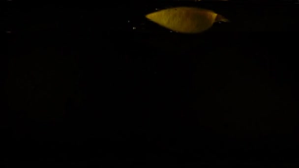 水の中でレモンの落下 スローモーション 黒の背景 — ストック動画