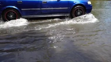 Yağmurdan sonra şehirde sel. Arabalar caddenin aşağısına gidiyor. Yavaş çekim.