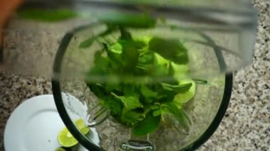 Mentha yaprakları salatalık parçalarının üzerine dökülür. Ağır çekim. Mutfakta çekim. Üst görünüm.