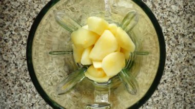 Muz parçaları elma parçalarının üzerine blender kasesine düşer. Ağır çekim. Mutfakta çekim. Üst görünüm.