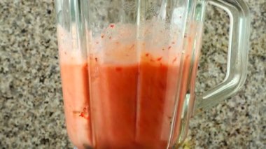 Elma, muz ve çilek karışımından karışıma kokteyl hazırlamak. Mutfakta çekim..