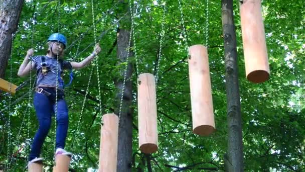 La fille l'adolescent surmonte les obstacles entre les arbres en hauteur. Tournage en été .