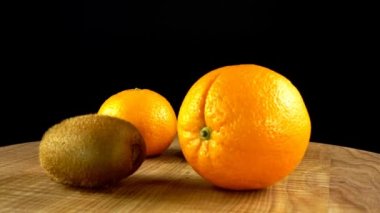 Siyah arka planda Mandarin, portakal, limon ve kivi. Hareketin tahtası kesiliyor.