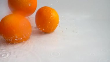 Sulu portakallar ve su sıçramaları. Yavaş çekim.