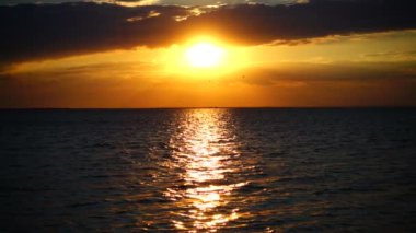 Denizin üzerinde gün batımı. Ağır çekim. Denize ateş etmek.