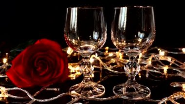 Şarap kadehleri ve gül arkaplanda parlak çelenkler.