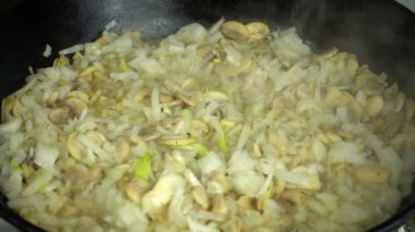 Şampiyonların soğanlı mantarlarının hazırlanması. Ağır çekim. Dökme demir tava.