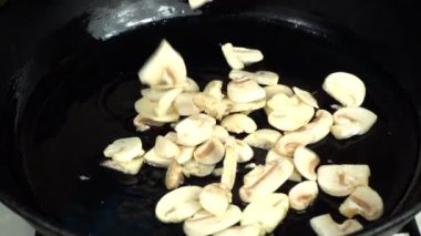 Şampiyon mantarları dökme demir tavaya düşer. Ağır çekim. Dökme demir tava.