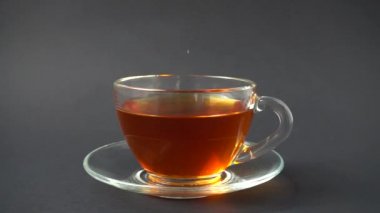 Şeker, çayla bardağa düşer. Yavaş çekim.