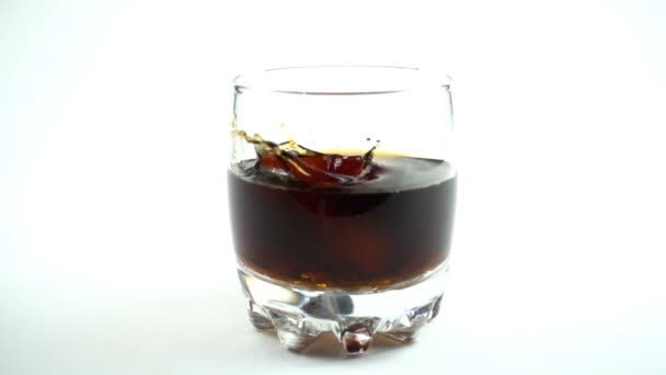 Des cubes de glace tombent dans un verre avec un Coca Cola. Au ralenti. 240 ips. Mouvement lent .