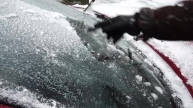 Kar ve buzdan bir arabanın ön camını temizliyorum. Kışın çekim..