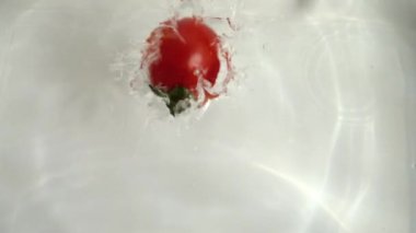 Kiraz domatesleri suya düşüyor. Yavaş çekim.