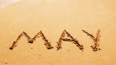 Kumsaldaki ayın isminin yazılı olduğu bir yazı. Sahilde çekim yapmak..