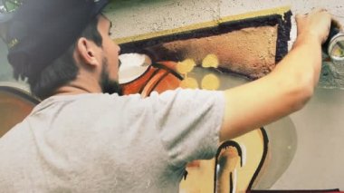 Sanatçı çitlere grafiti çiziyor. Çitin üzerindeki graffiti.