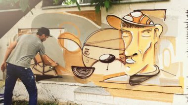 Sanatçı çitlere grafiti çiziyor. Çitin üzerindeki graffiti.