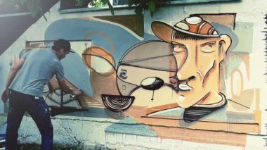 Sanatçı çitlere grafiti çiziyor. Çitin üzerindeki graffiti.