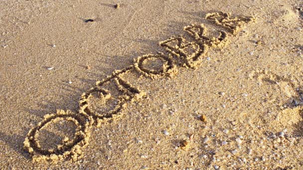 砂の上の碑文10月 碑文は海の波で洗い流される 浜辺での銃撃戦 — ストック動画