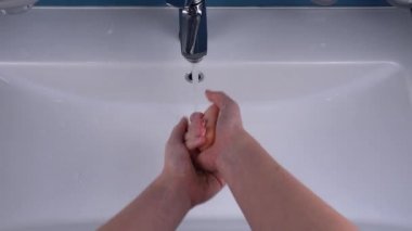 Kız ellerini lavabonun üzerinde sabunla yıkıyor..