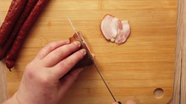 Aşçı domuz pastırmalı füme sosis keser..