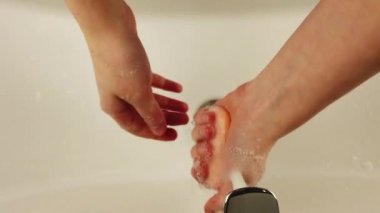 Kız ellerini lavabonun üzerinde sabunla yıkıyor..