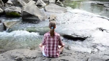 Kız dağ nehri taşları üzerinde yoga yapıyor. Yazın çekim..