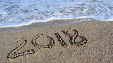 Kuma 2018 yazıtları. Yazı bir deniz dalgası tarafından silinmiş. Sahilde çekim yapmak..