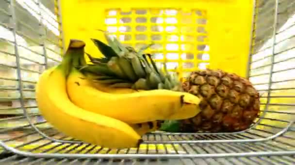 スーパーマーケットのカート カートにバナナとパイナップルを入れています カートの動き 製品の選択 — ストック動画