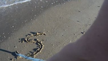 Kuma yazılan SOS yazısı. Sahilde çekim yapmak..