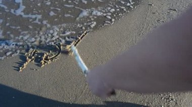 Kumlu sahilde Bali yazıtları. Sahilde çekim yapmak..