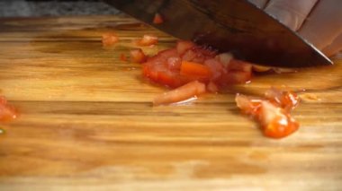 Aşçı domatesleri kesme tahtasıyla keser..