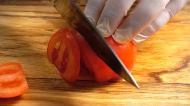 Aşçı domatesleri kesme tahtasıyla keser..