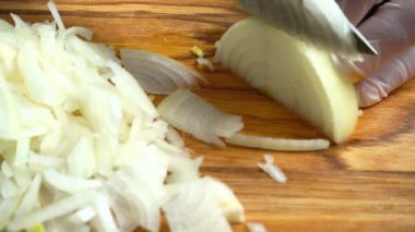Ahşap tahtanın soğanını bıçakla kesen şefin elleri. Yemek hazırlığı. Sağlıklı beslenme ve yaşam tarzı.