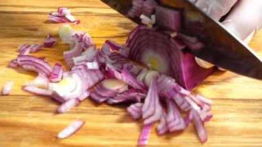 Ahşap tahtanın soğanını bıçakla kesen şefin elleri. Yemek hazırlığı. Sağlıklı beslenme ve yaşam tarzı.