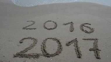 Sahilde çekim yapmak. Yeni Yıl 2017 geliyor - 2016 ve 2017 yazıtları plaj kumlarında, dalga 2016 rakamlarını kapsıyor..