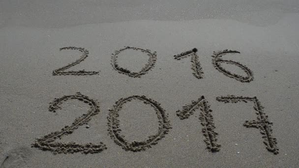 在海滩上拍摄 2017年新年即将到来 在海滩沙滩上写下2016年和2017年的名字 海浪几乎覆盖了2016年的数字 — 图库视频影像