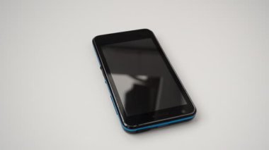 Siyah modern akıllı telefon. Yüzeyde beyaz arkaplanda izole siyah, beyaz ekranlı akıllı telefon var..