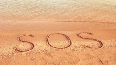 Kuma yazılan SOS yazısı. Sahilde çekim yapmak..