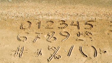 Kumsala yazılmış rakamlar ve işaretler. Sahilde çekim yapmak..