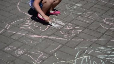 Çocuk tebeşirle çiziyor. Bir aile günü onuruna yapılan eylemler. Yazın çekim..