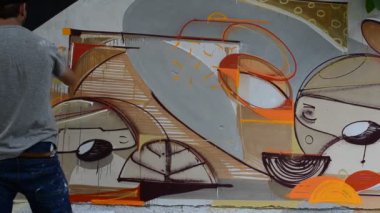 Ressam graffiti çiziyor, piposu olan kişinin resmi..