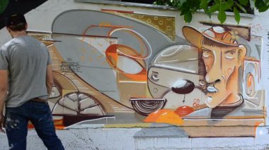 Ressam graffiti çiziyor, piposu olan kişinin resmi..