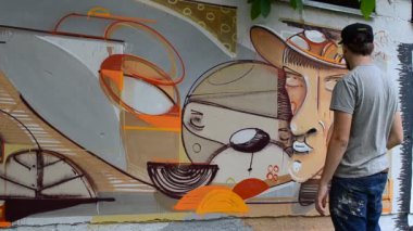 Ressam graffiti çiziyor, piposu olan kişinin resmi..