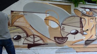 Ressam graffiti çiziyor, piposu olan kişinin resmi..