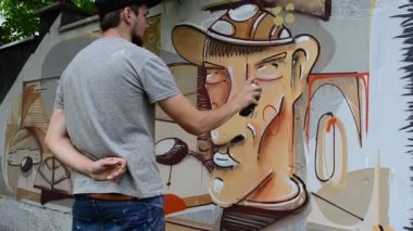 Ressam graffiti çiziyor, piposu olan kişinin resmi..