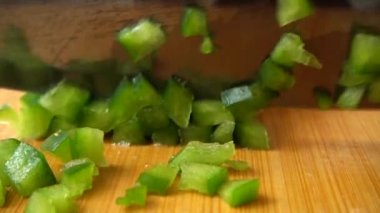 Aşçı bir bıçakla yeşil tatlı biberi keser. Yavaş çekim.