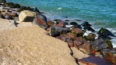 Deniz dalgaları taşlara çarpıyor. Deniz kıyısında ateş ediyorlar. Yavaş çekim.